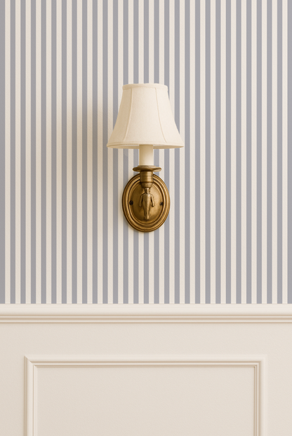 Blue grey striped wallpaper with brass wall sconce in elegant room setting.