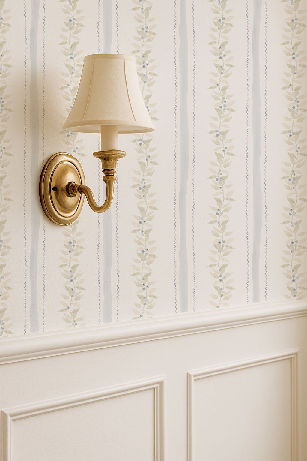 Blueberry vines wallpaper with sage and gold vines on cream background in elegant room with wall sconce.